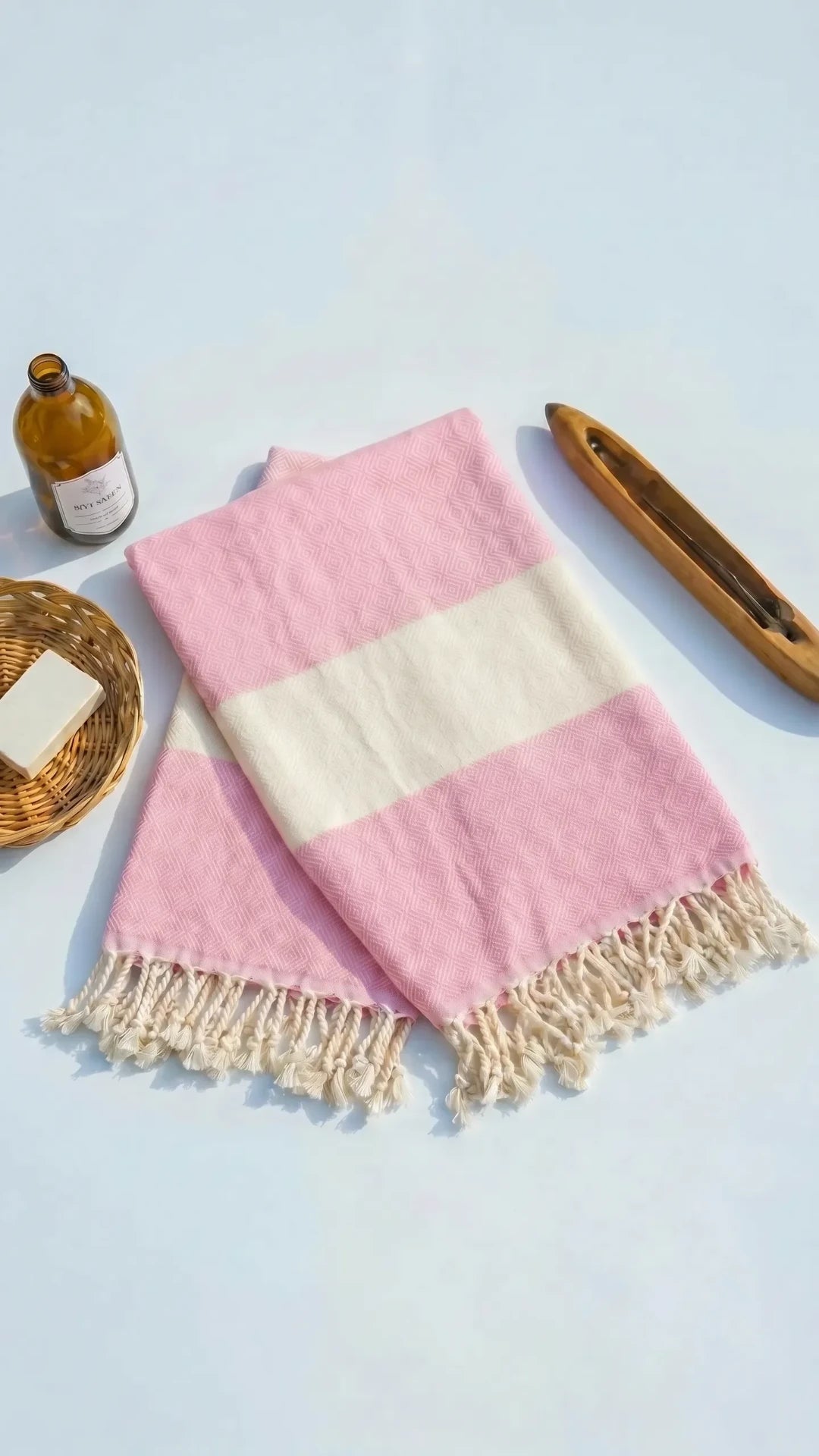 Pink peshtemal folded with soap and wooden accessories