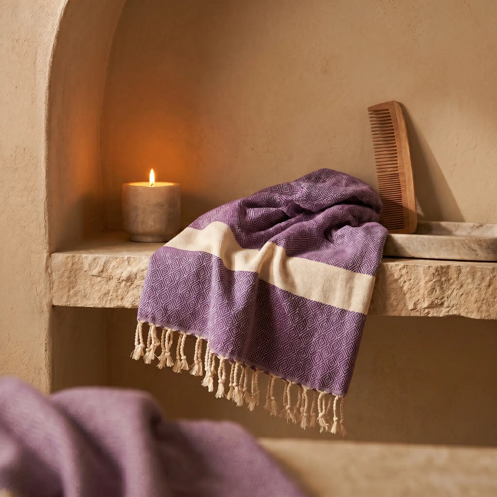 Purple peshtemal in a warm stone bathroom niche with candle